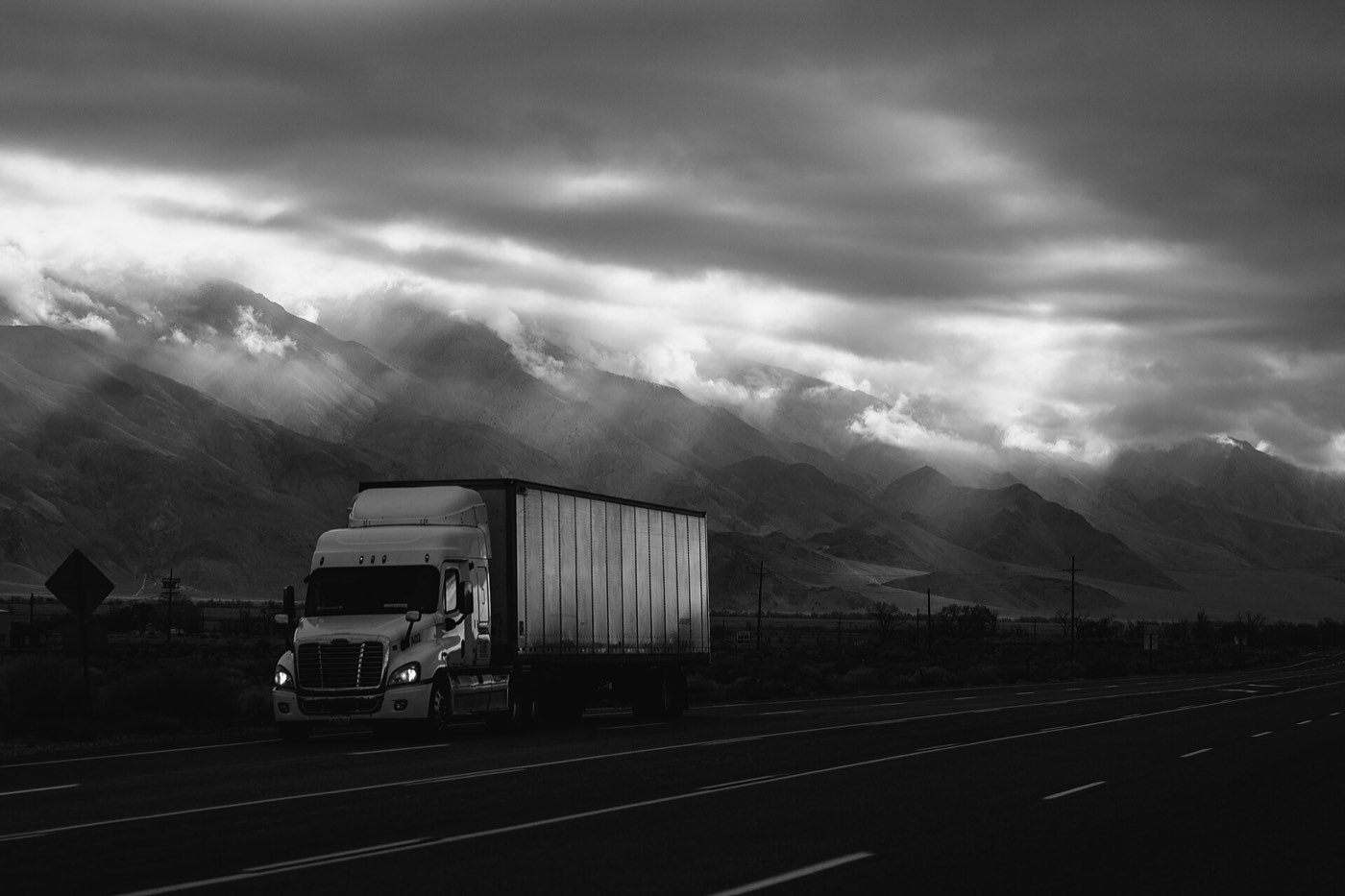 A dry van on a desert highway under storm light